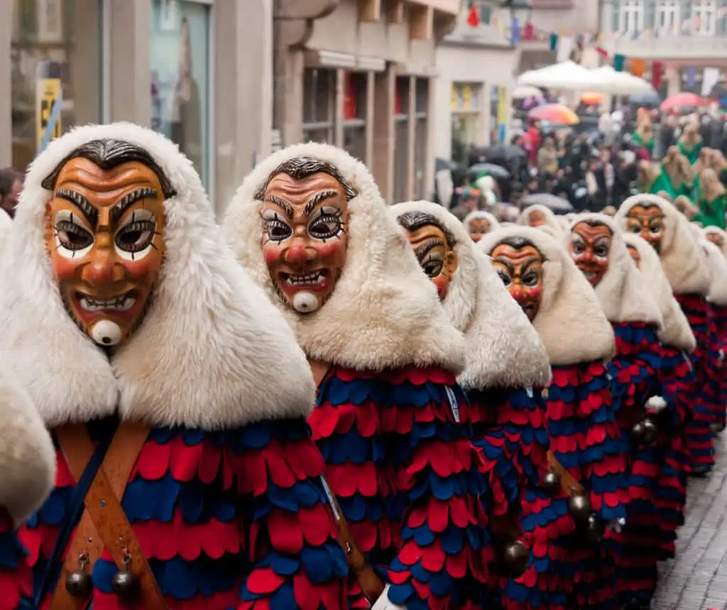 Eine Gruppe maskierter Menschen auf einer Straße, die den Fasching in Österreich feiert.